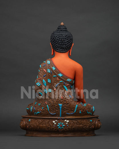 Back view of Shakyamuni Buddha statue showing oxidized copper finish and floral robe carving