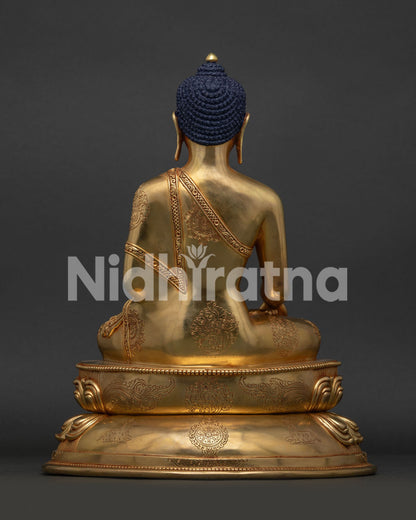 Back view of Shakyamuni Buddha statue showing wisdom wheel and deer engraved on lotus base.