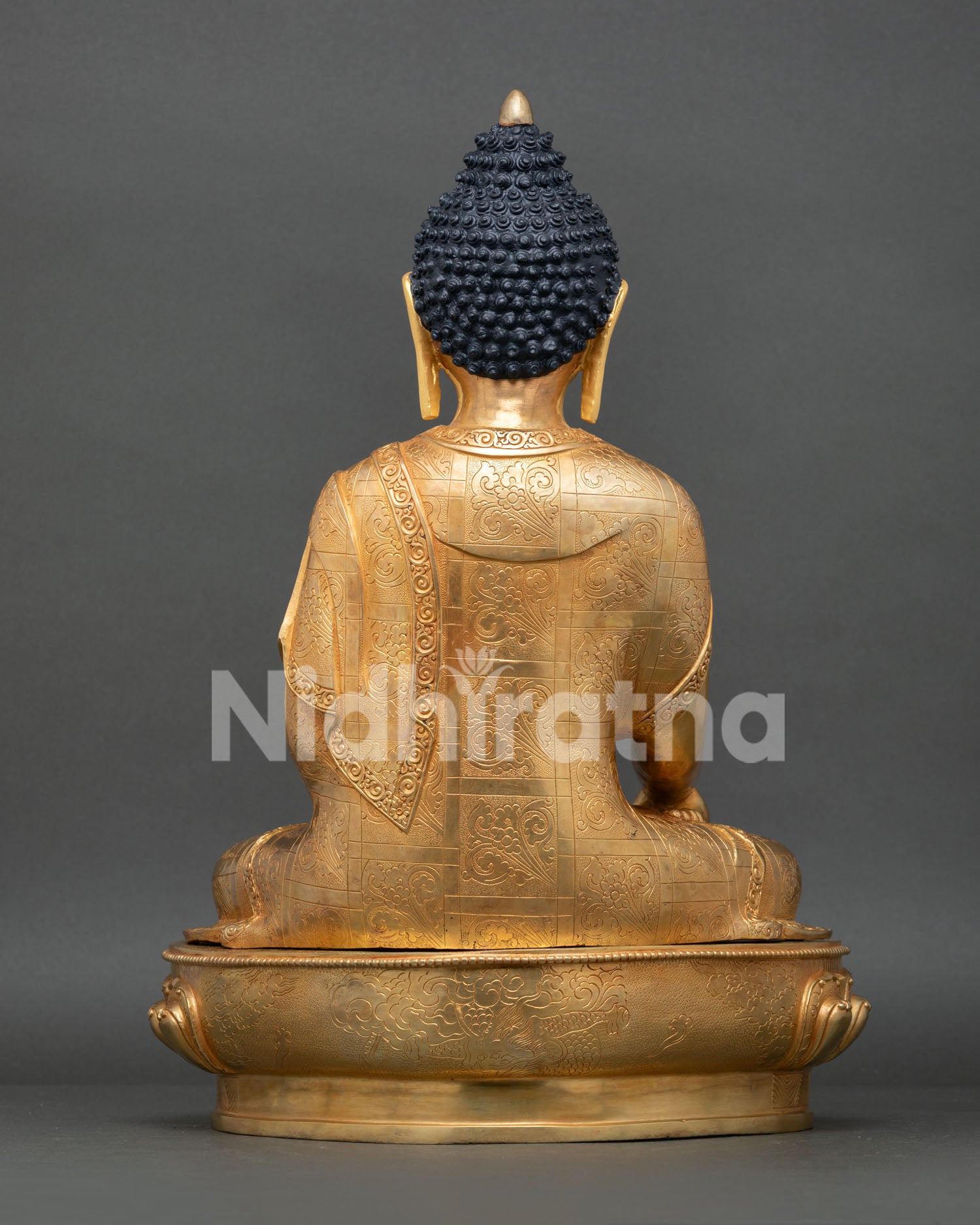back view of shakyamuni buddha statue with detailed robe carvings and lotus base