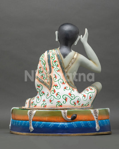 back view of tibetan buddhist milarepa statue with floral robe and deer hide draped pedestal