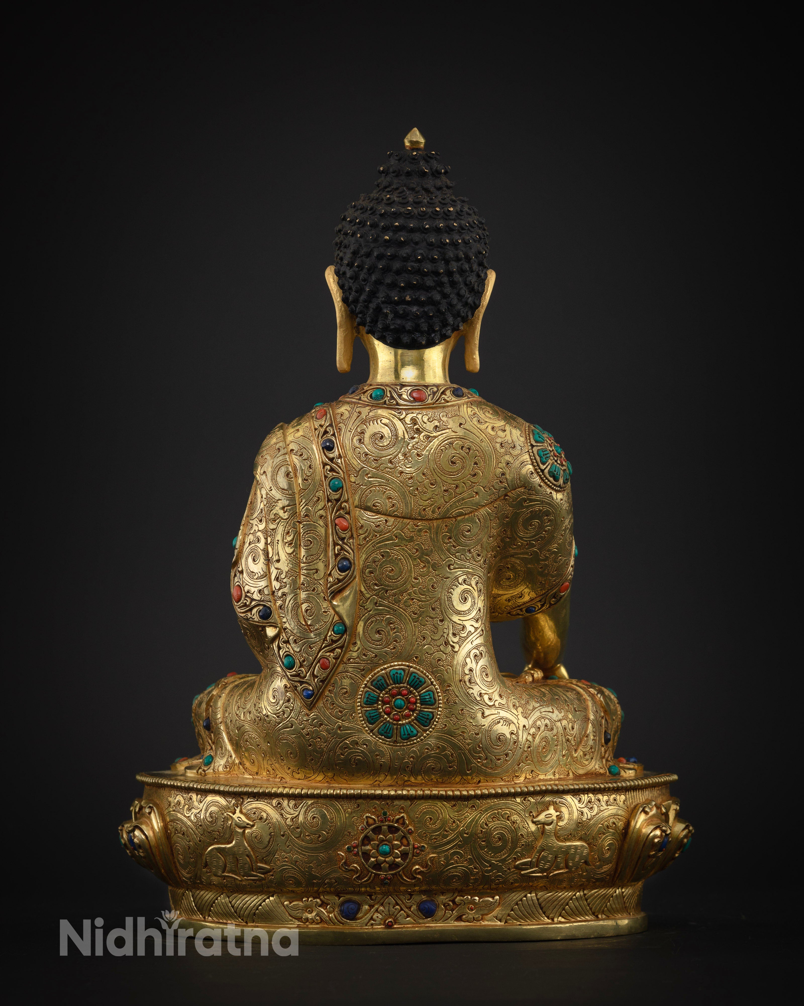 Back view of Shakyamuni Buddha statue showing lotus throne and deer motif base