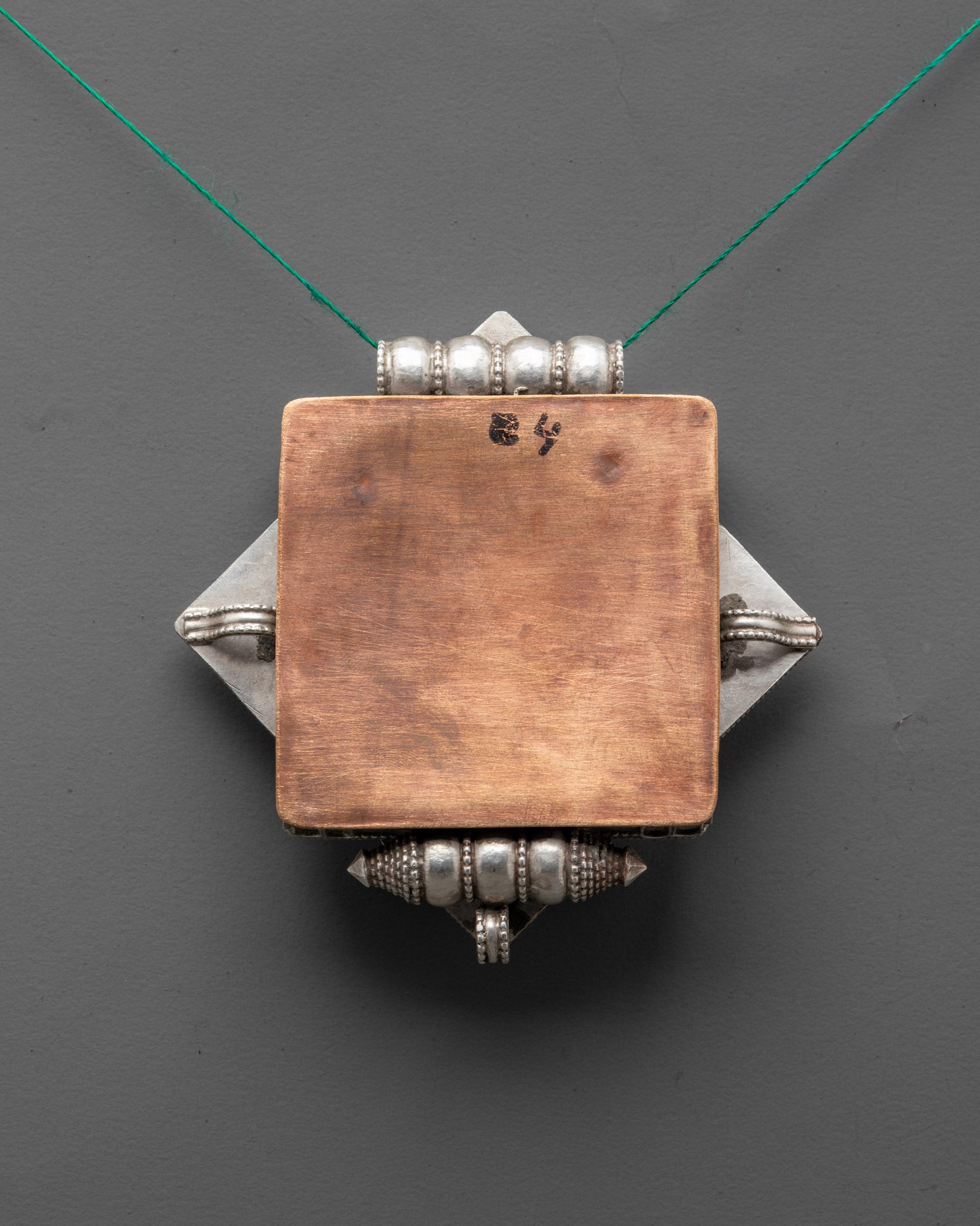back view of Tibetan amulet locket highlighting artisan design and traditional symbolism