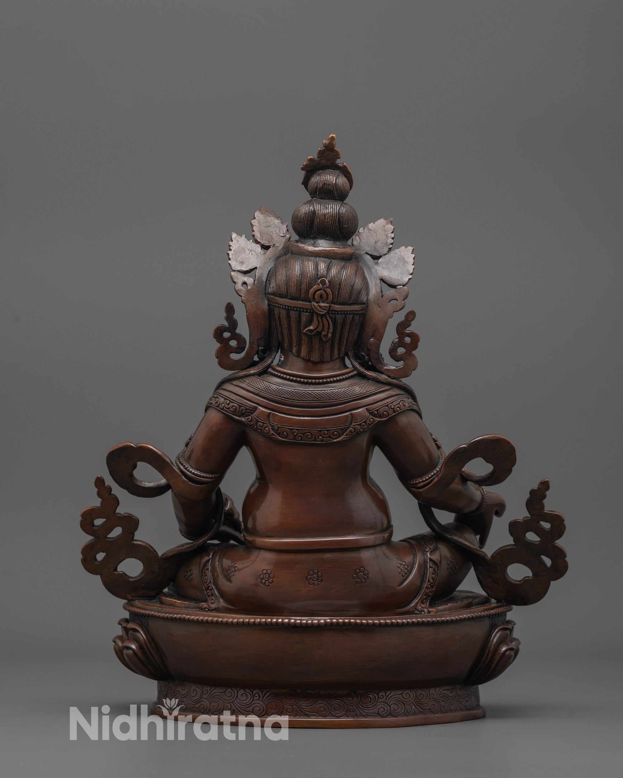 back view of dzambhala wealth statue displaying robe details and dark oxidized copper texture