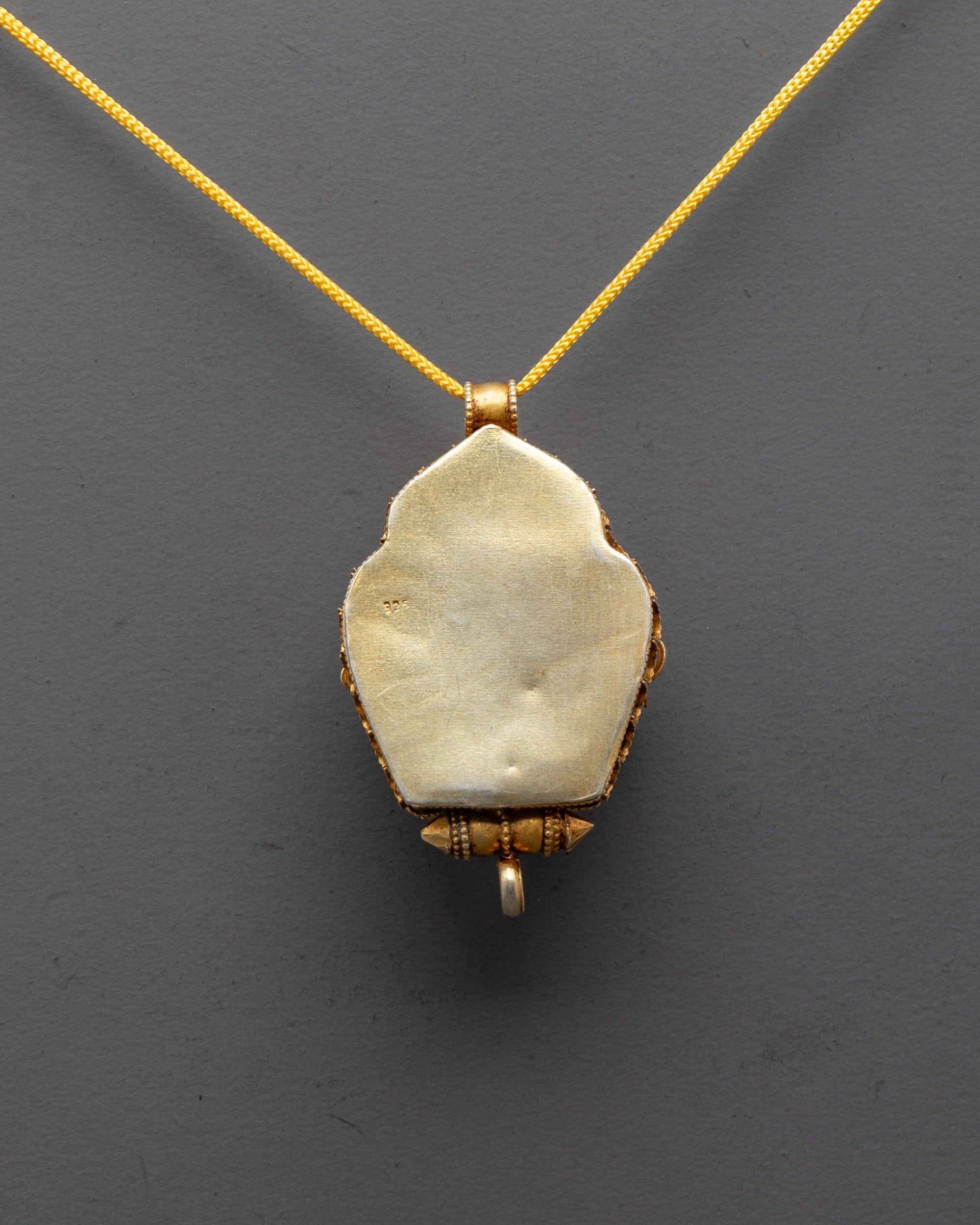 back view of intricate filigree design on gold-plated Dzambhala pendant from Patan Nepal