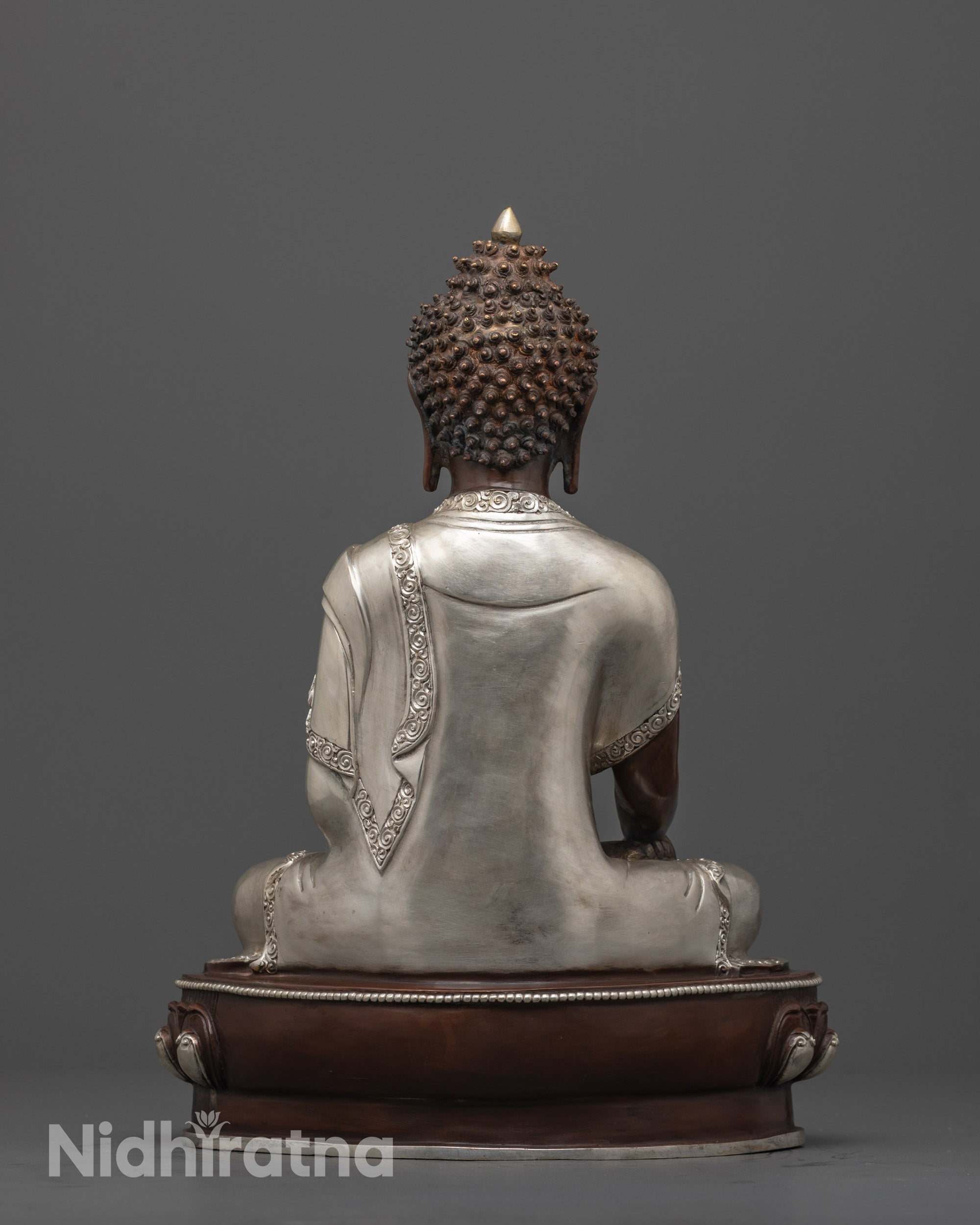 back view of shakayamuni buddha statue showing detailed silver monk’s robe craftsmanship