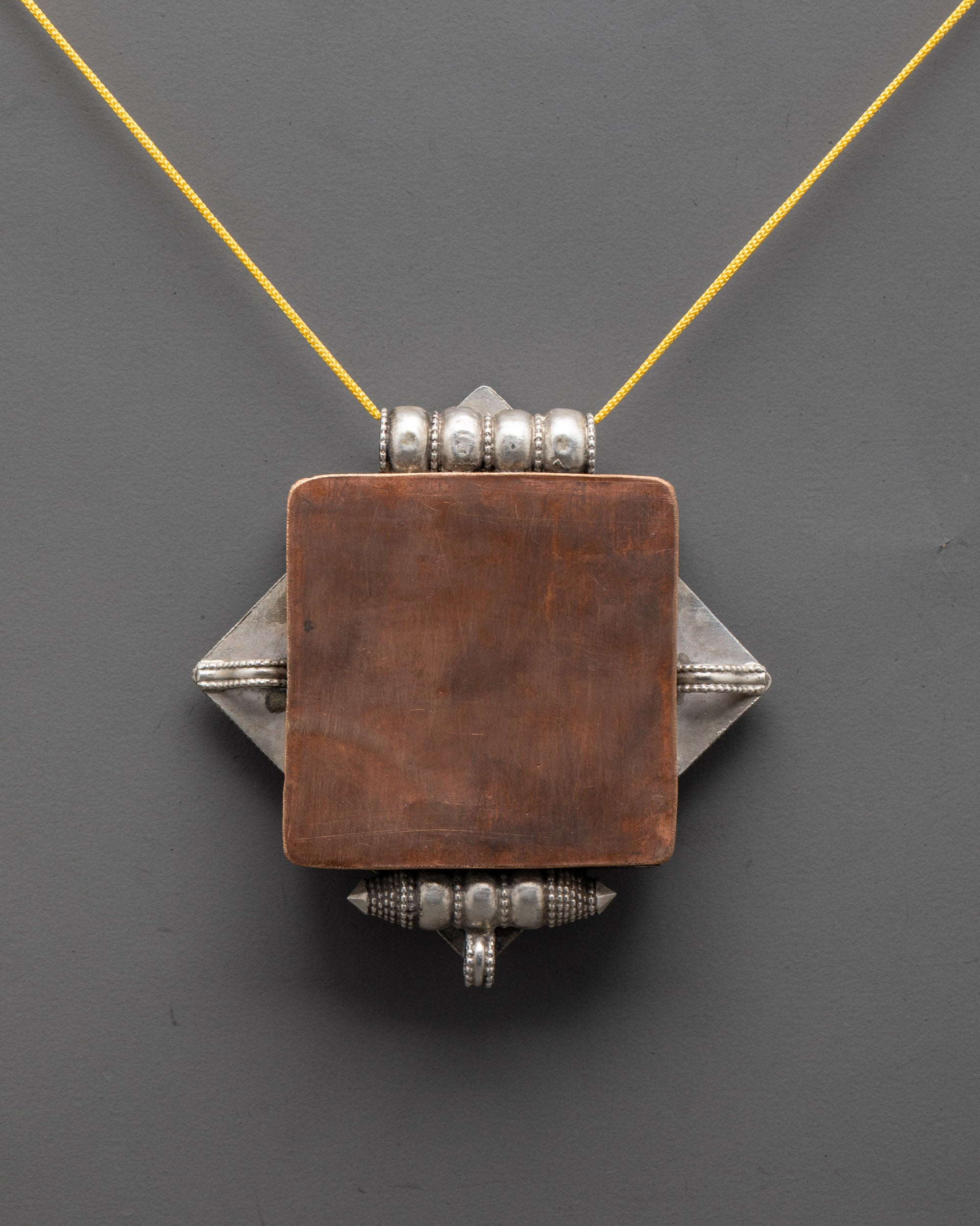 back view of silver tibetan locket with intricate filigree symbolizing blessings and harmony