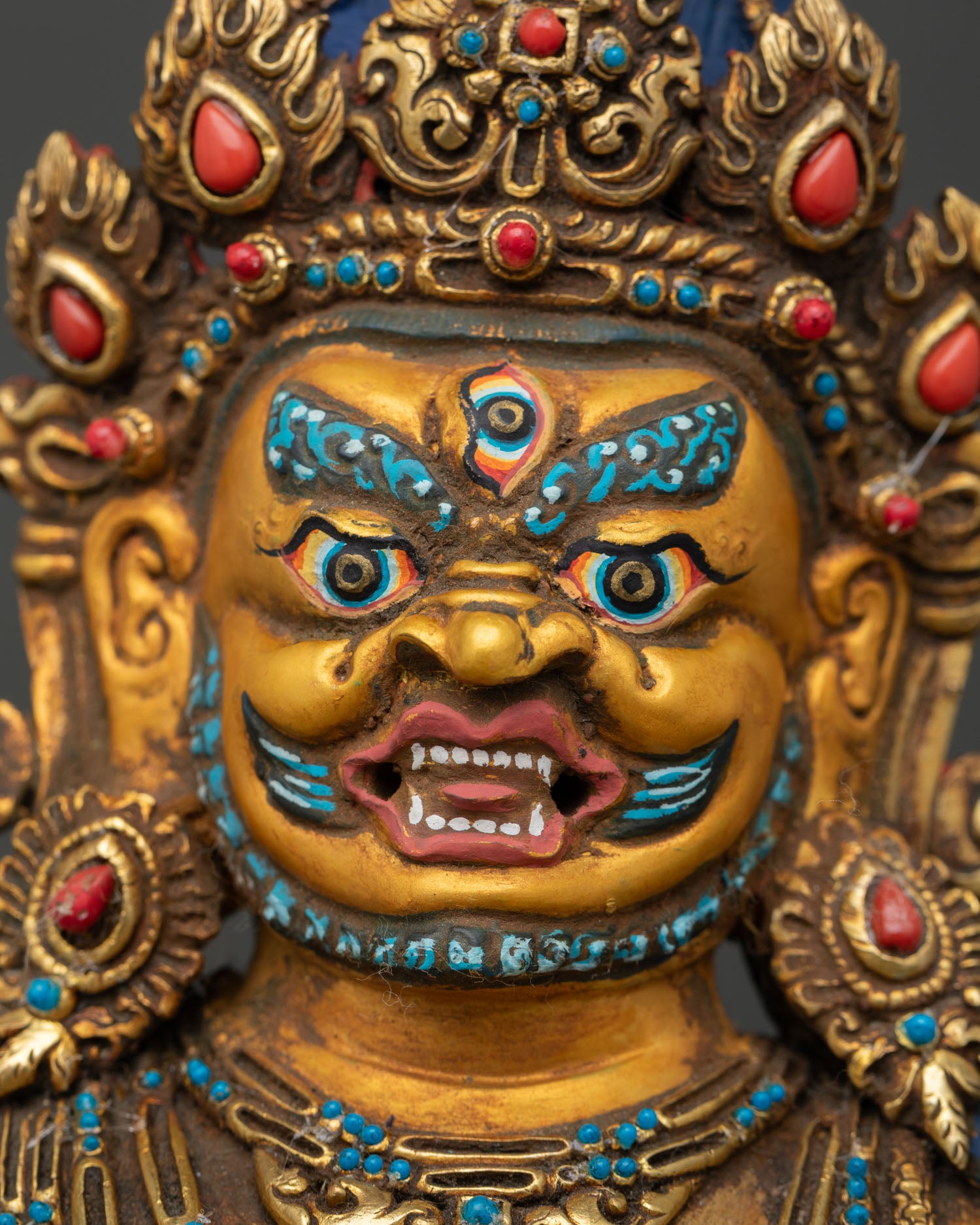 Black Dzambhala face close up with 24K gold-painted details and serene Buddhist expression