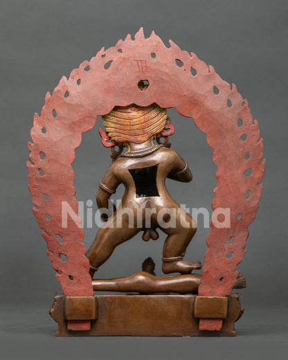 Black Dzambhala sculpture with blazing halo standing over subdued figure in traditional Tibetan Buddhist art
