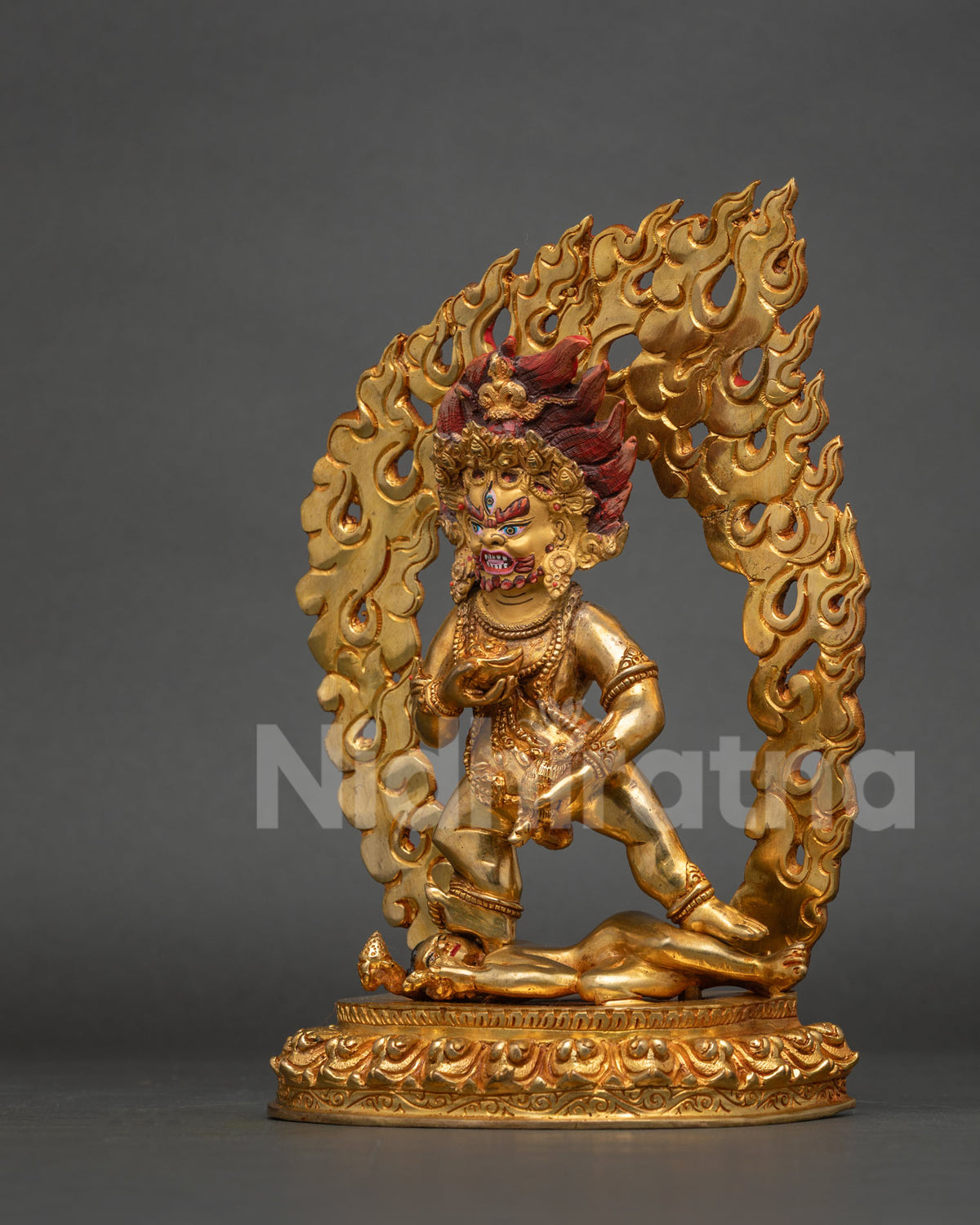 Black dzambhala statue holding jewel spitting mongoose and skull cup.