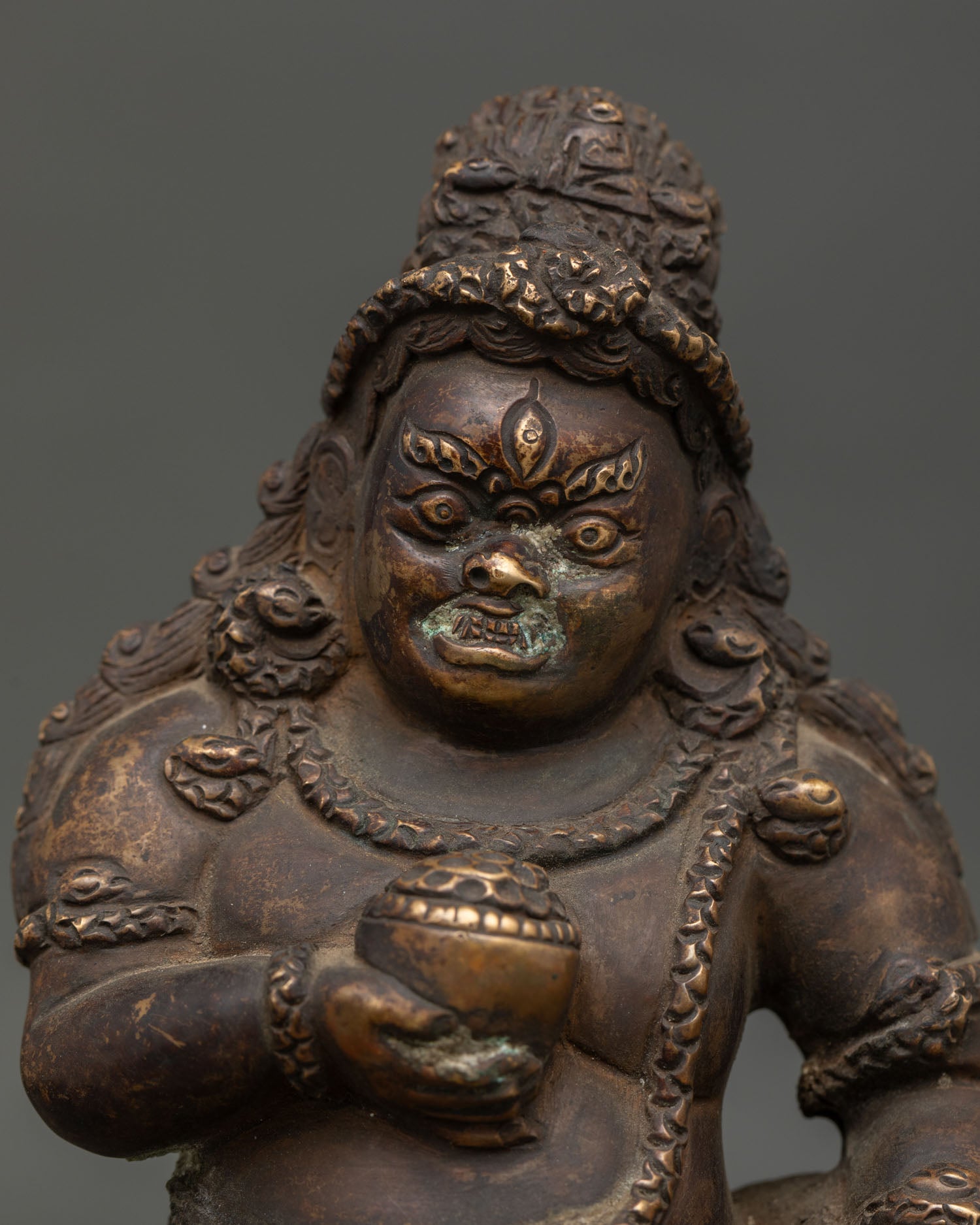 Black Dzambhala Statue holding skull cup and mongoose in wrathful posture.