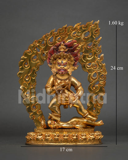 Black dzambhala statue standing on lotus pedestal with flaming halo and mongoose.