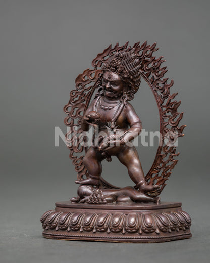 Black dzambhala wealth deity standing on lotus pedestal holding mongoose and kapala.