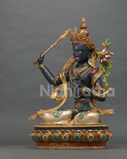 Black Manjushri statue side profile with raised flaming sword and flowing gold gilded scarves
