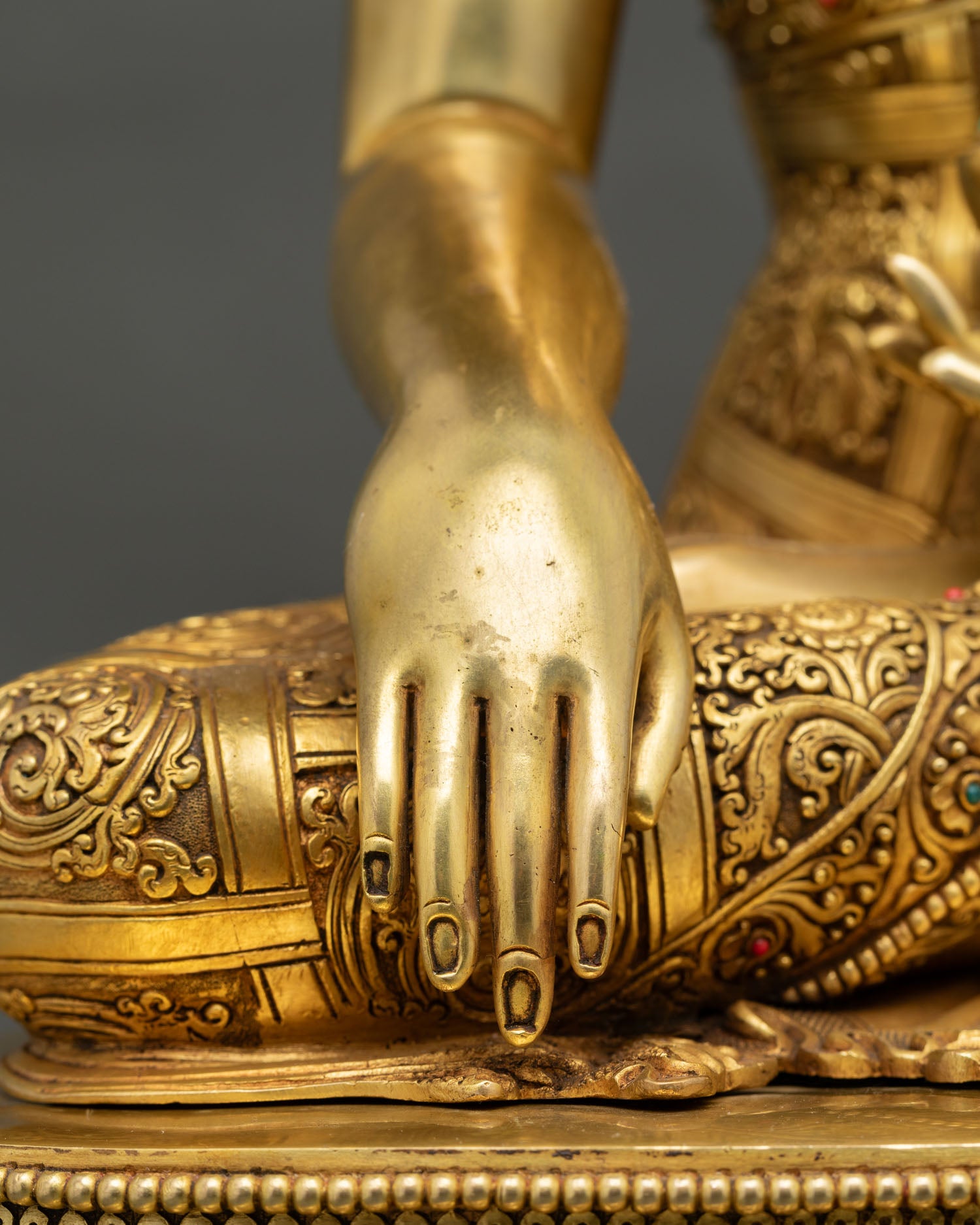 Buddha bhumisparsha mudra hand gesture, gold-gilded fingers, intricate work