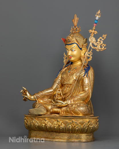 Buddhist Guru Rinpoche sculpture holding a vajra, trident, and skull cup topped with a vase