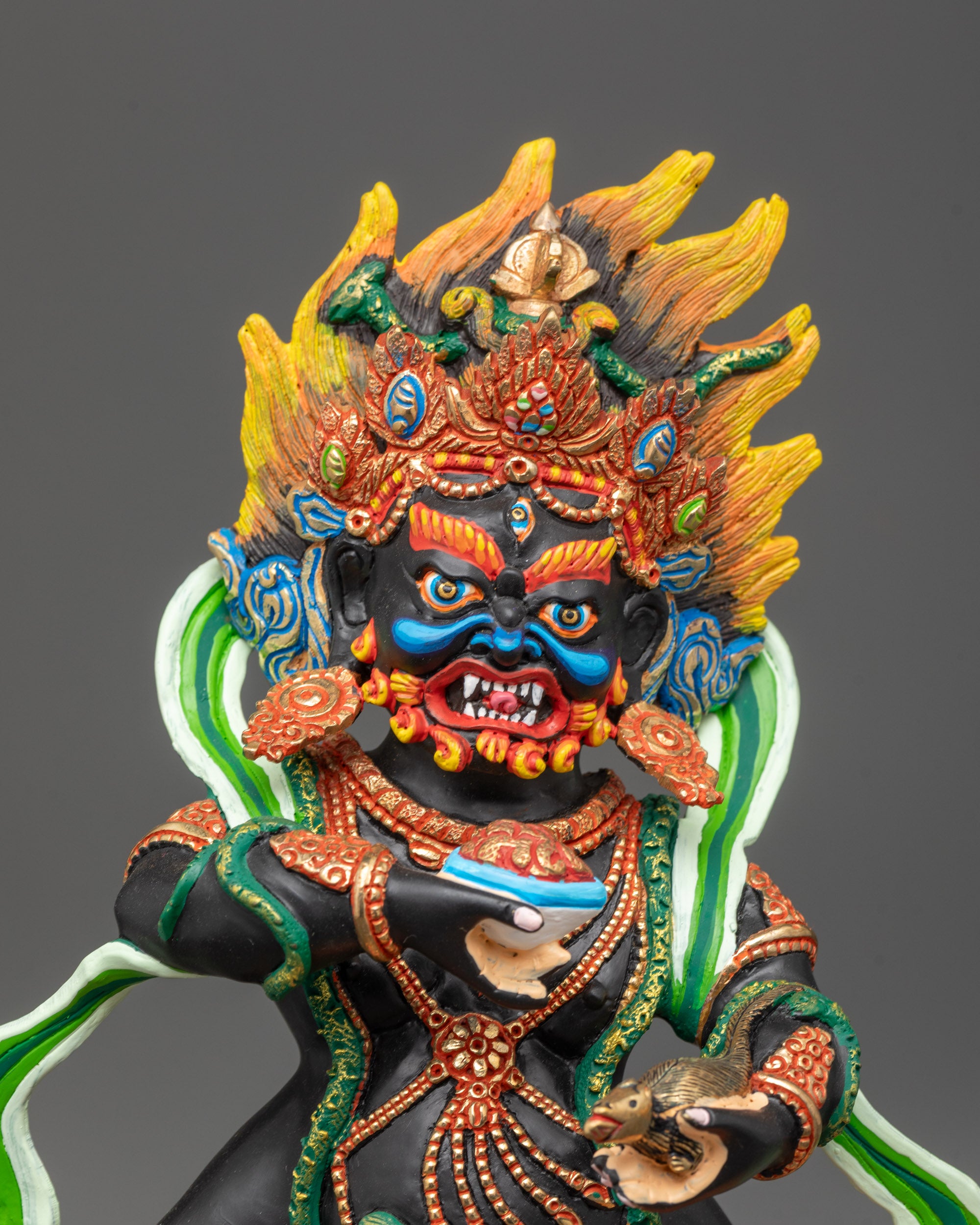 Close up Black Dzambhala copper statue holding skullcup and jewel spitting mongoose
