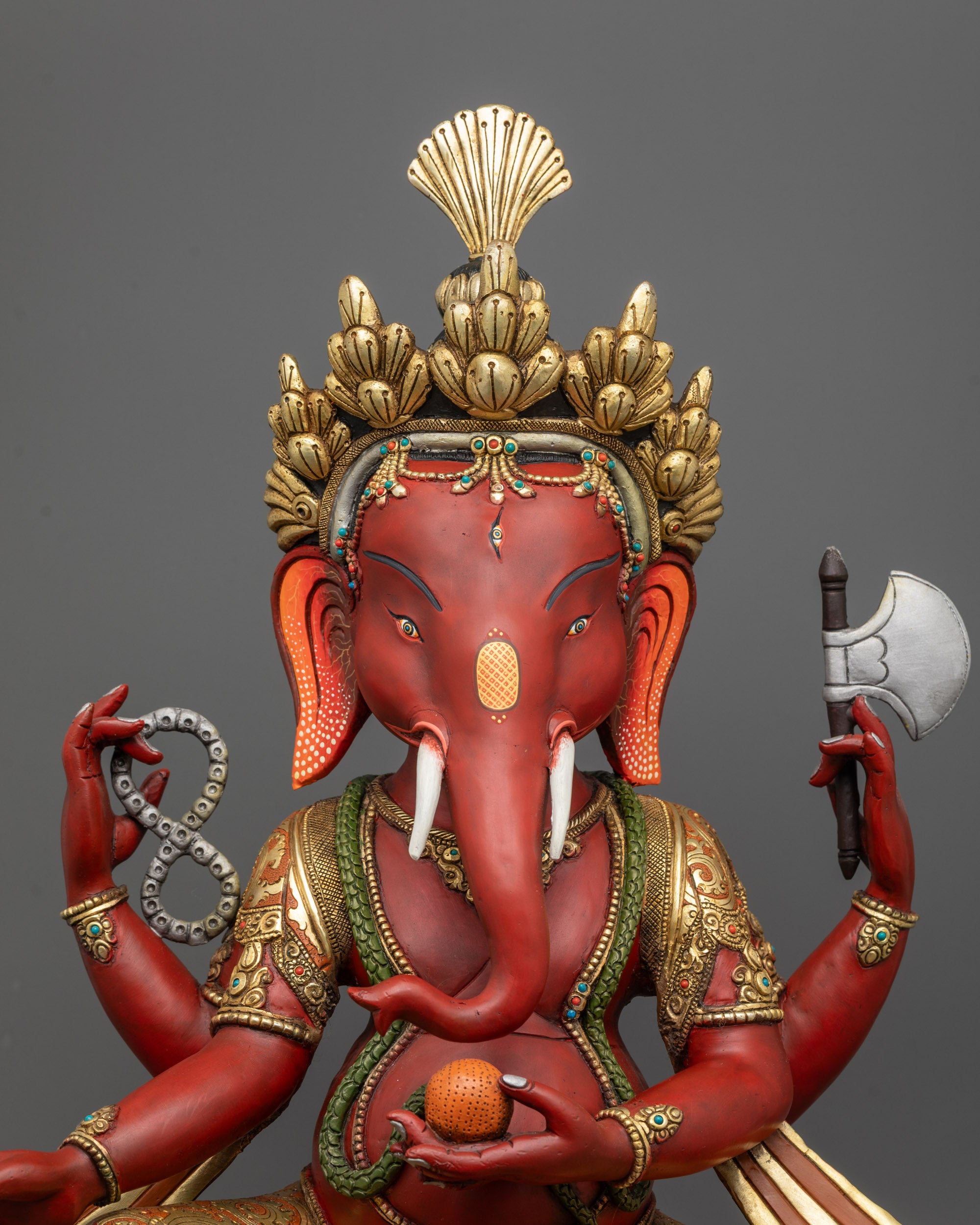 Close-up of handcrafted Red Ganesh statue showing intricate details and gold-plated highlights