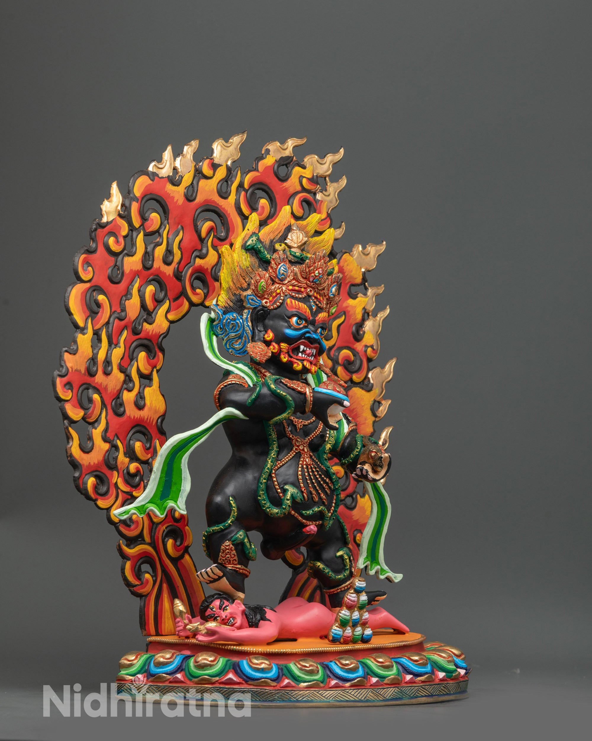 Side angle Black Dzambhala sculpture with black body and flowing green robe on lotus

