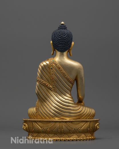 Back view of Buddha statue showing carved robe patterns and gold fire-gilded body