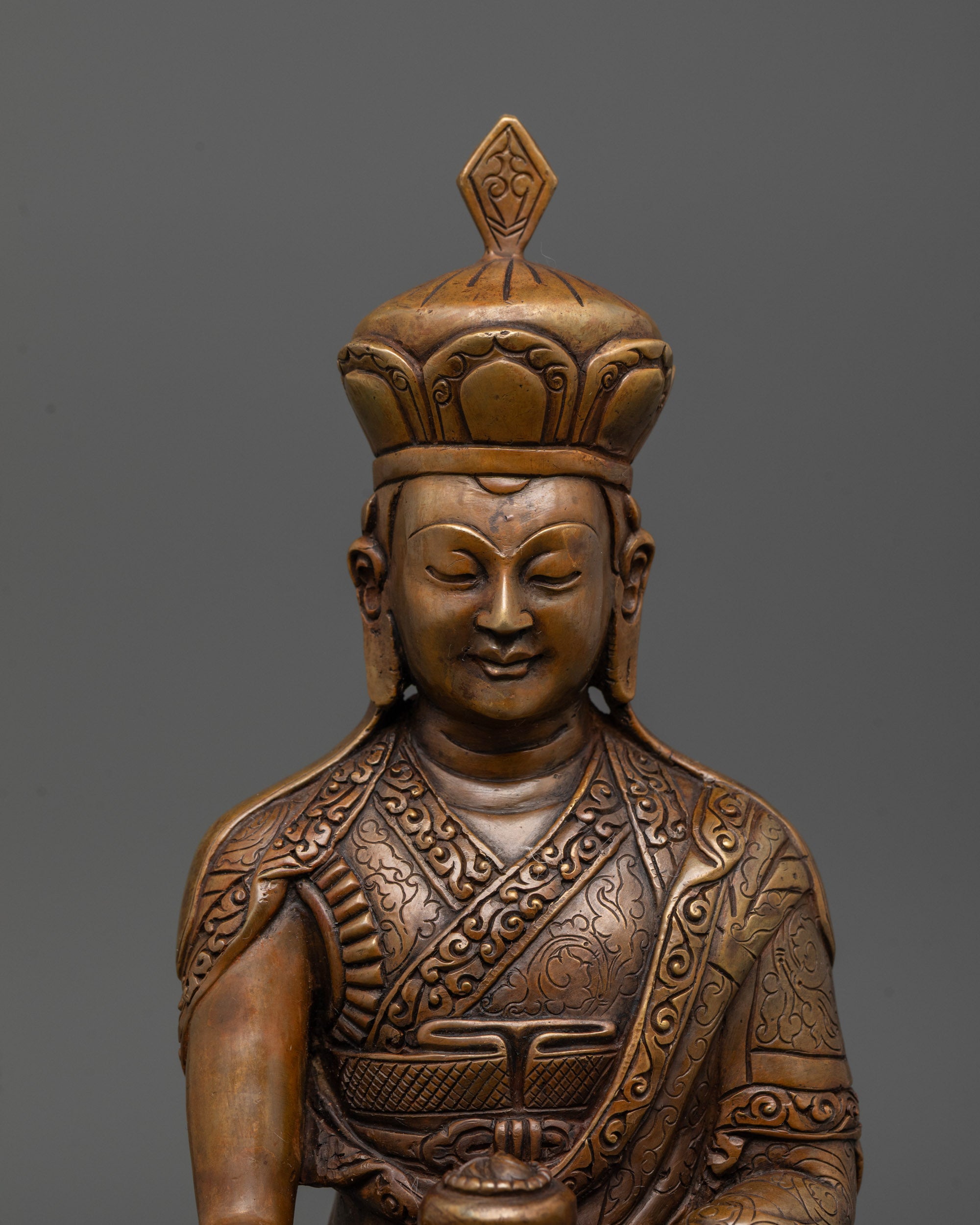 close-up of oxidized karmapa statue showing alms bowl and intricate facial details
