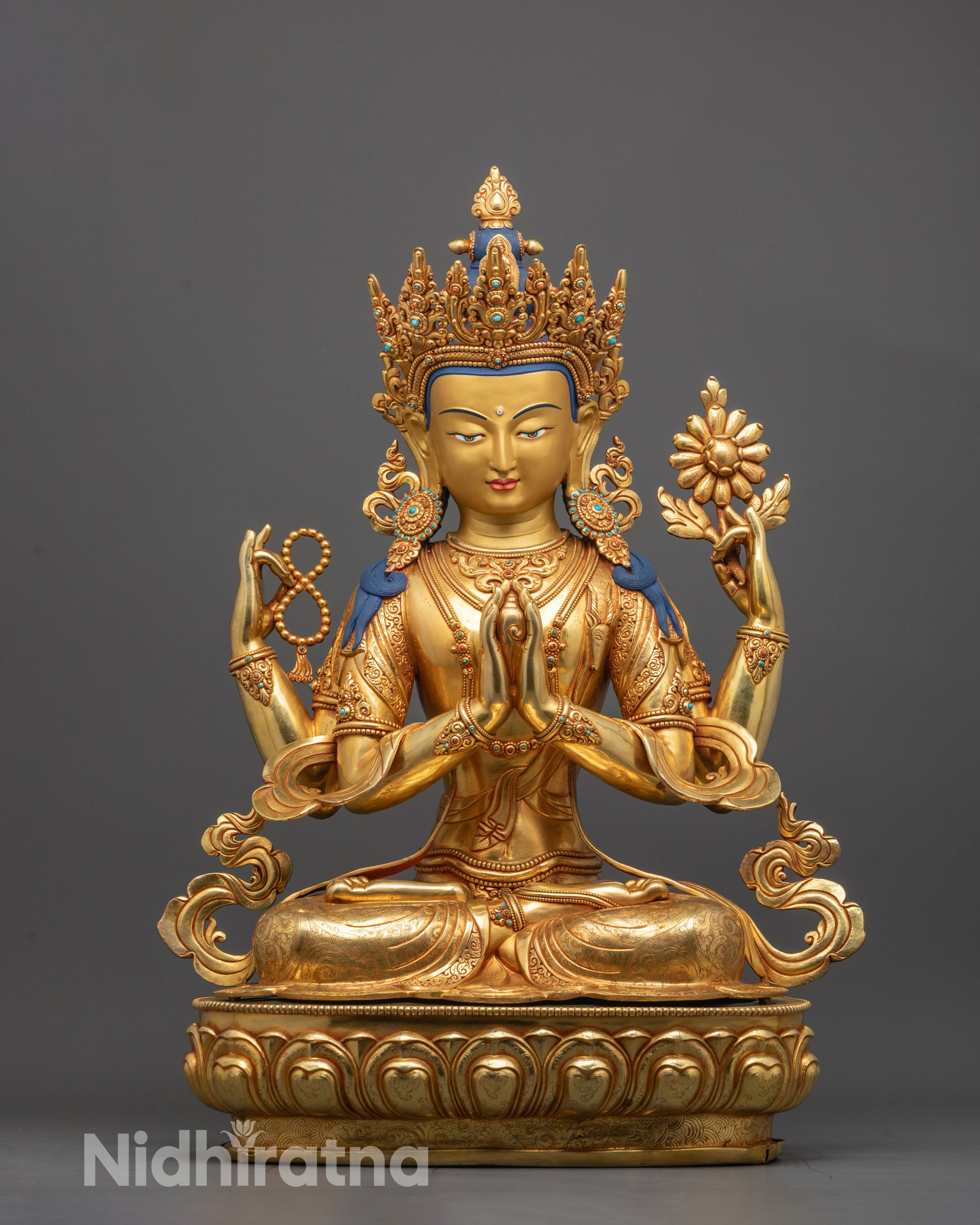 Front view of Chenrezig statue with gold gilding and four arms holding sacred objects