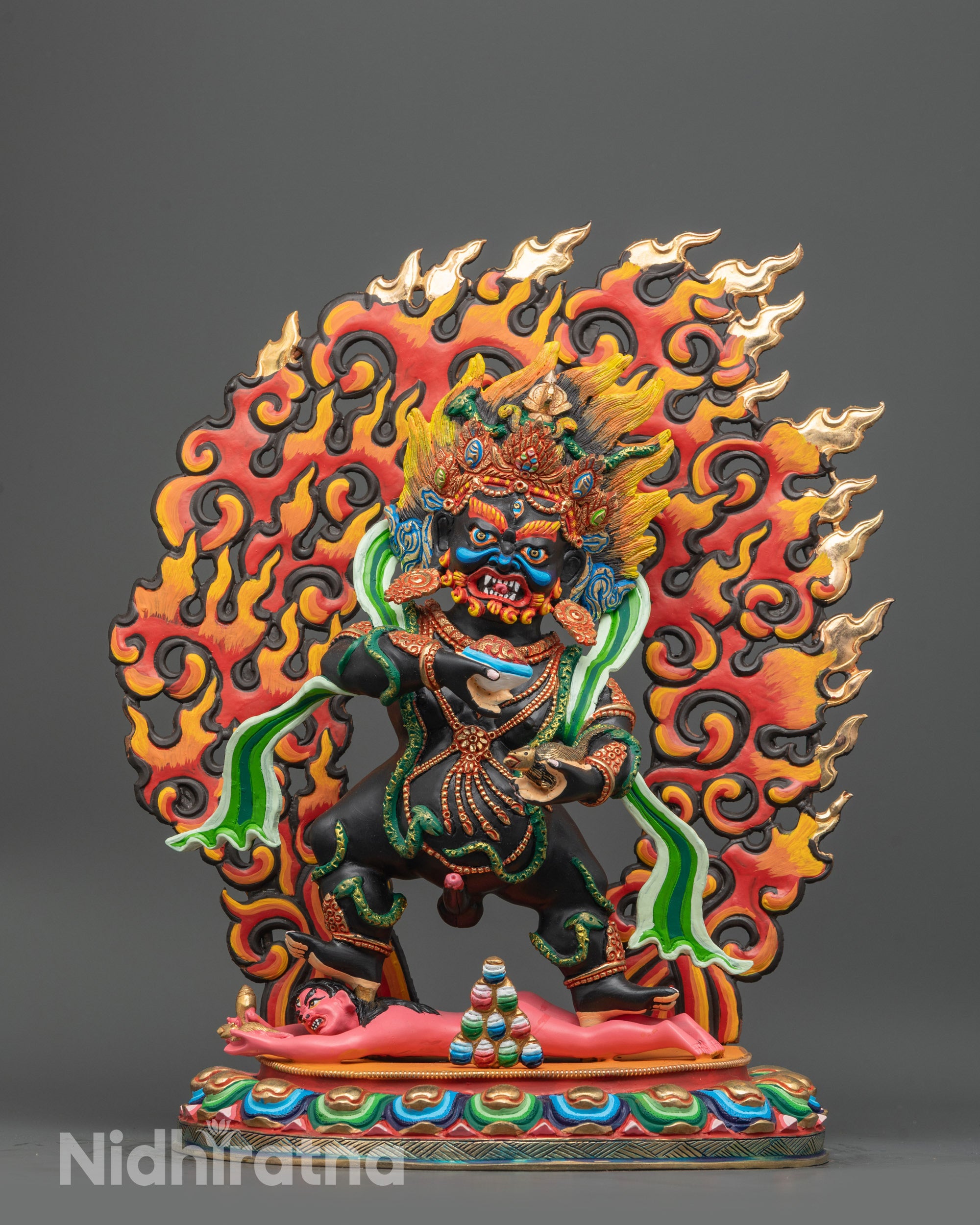Front view Black Dzambhala statue with green robe and wrathful halo on lotus base
