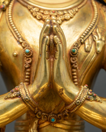 Chenrezig statue hands in prayer gesture at heart with gold fire-gilded bracelets, close-up
