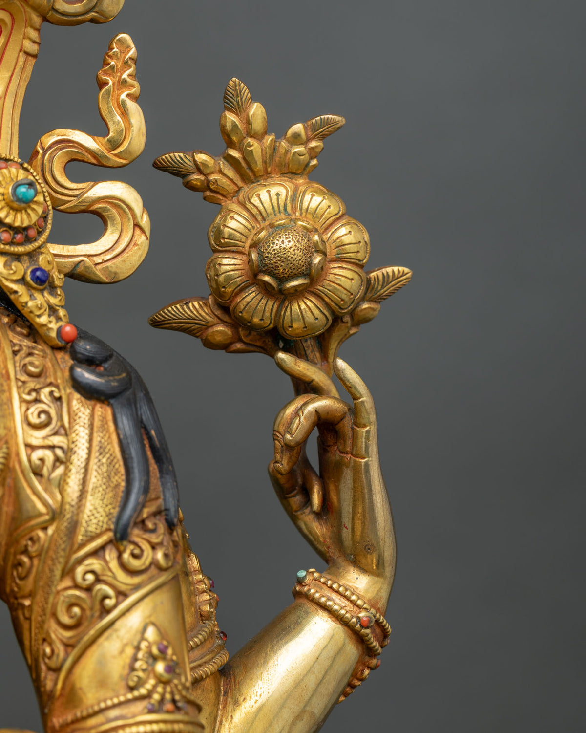 Chenrezig statue upper left hand holding a blooming lotus flower, close-up detail