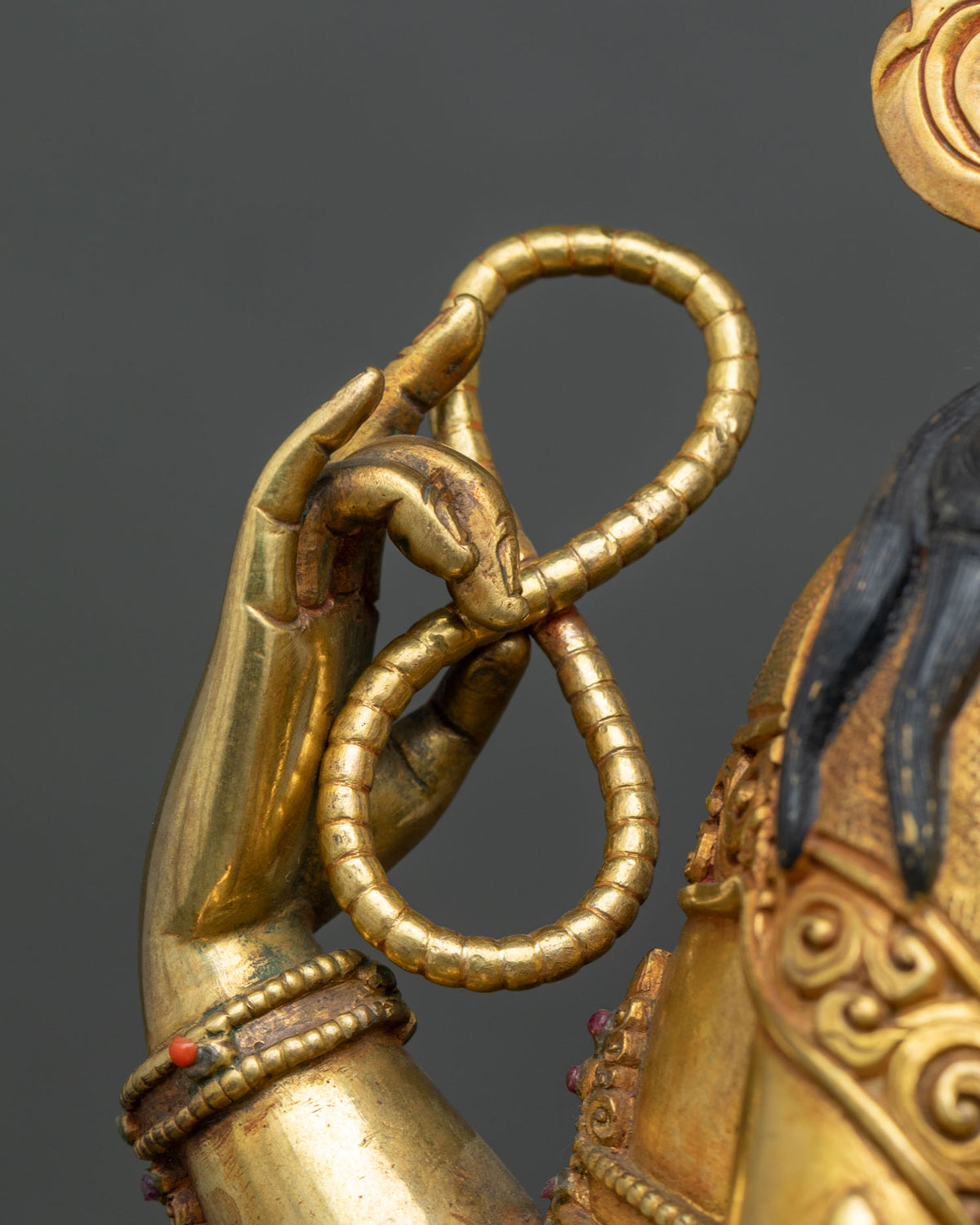 Chenrezig statue upper right hand holding a gilded rosary, close-up detail