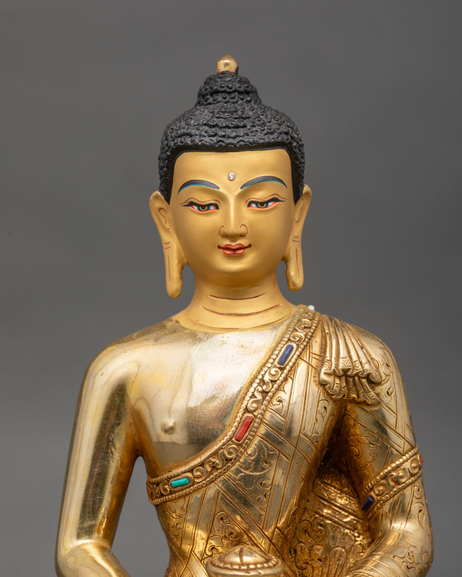 Close up Amitabha Buddha gold painted face with semi precious stones detail