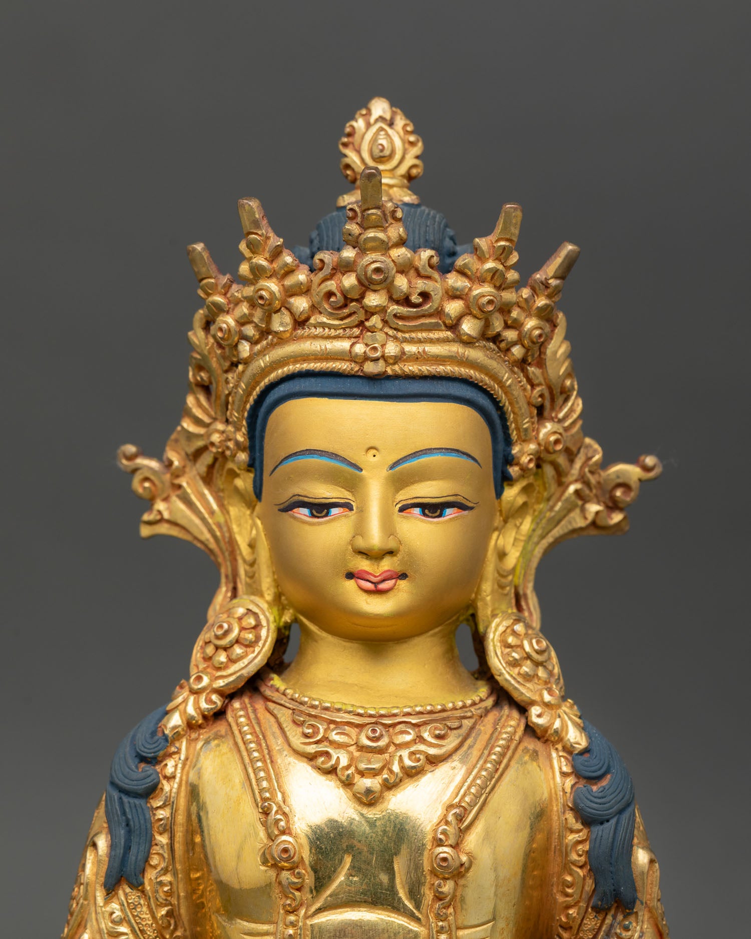Close up of Amitayus Bodhisattva statue serene gold painted face detail copper gold gilded Nepal