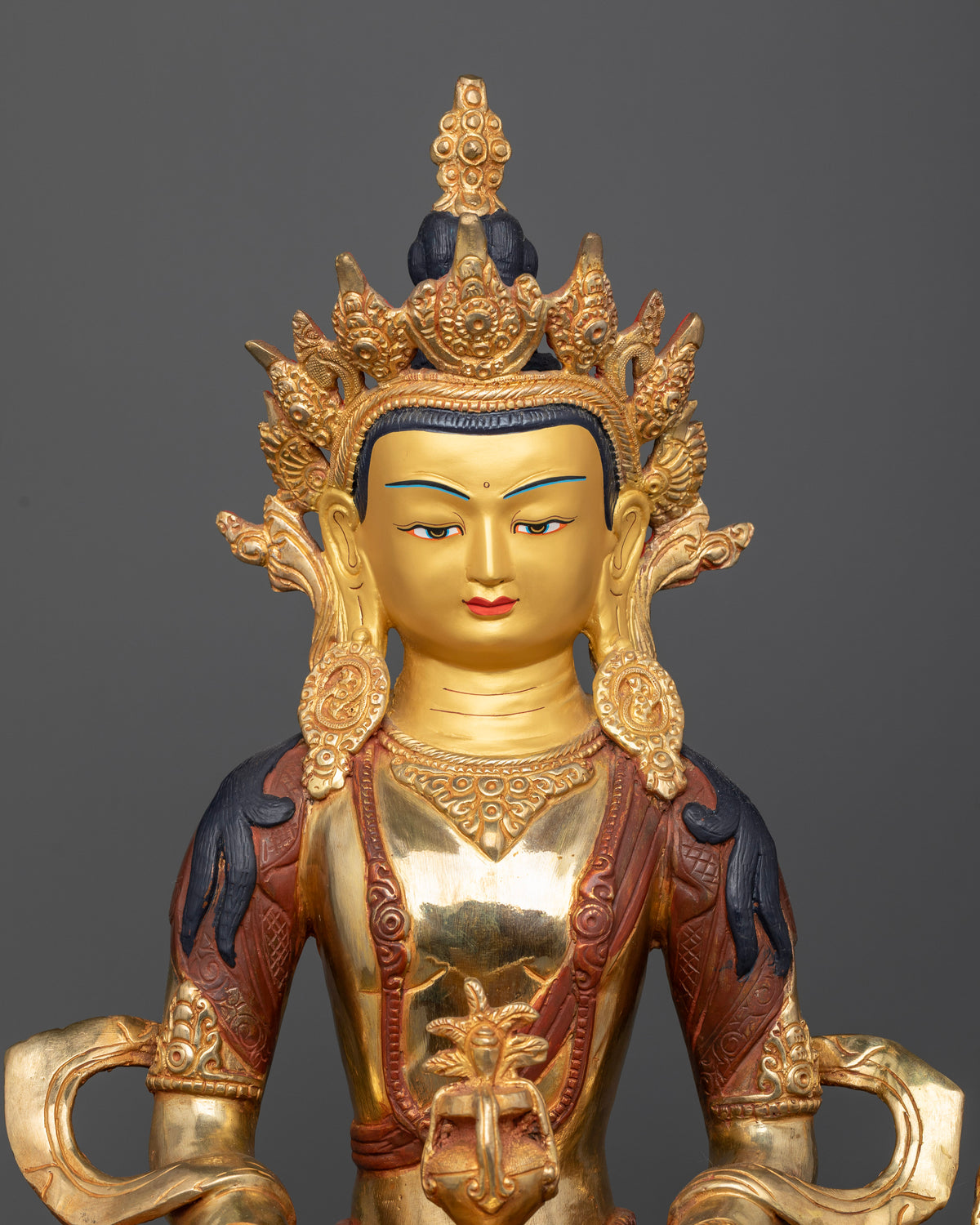Close up Amitayus statue with 24K gold painted face and jewel crown.