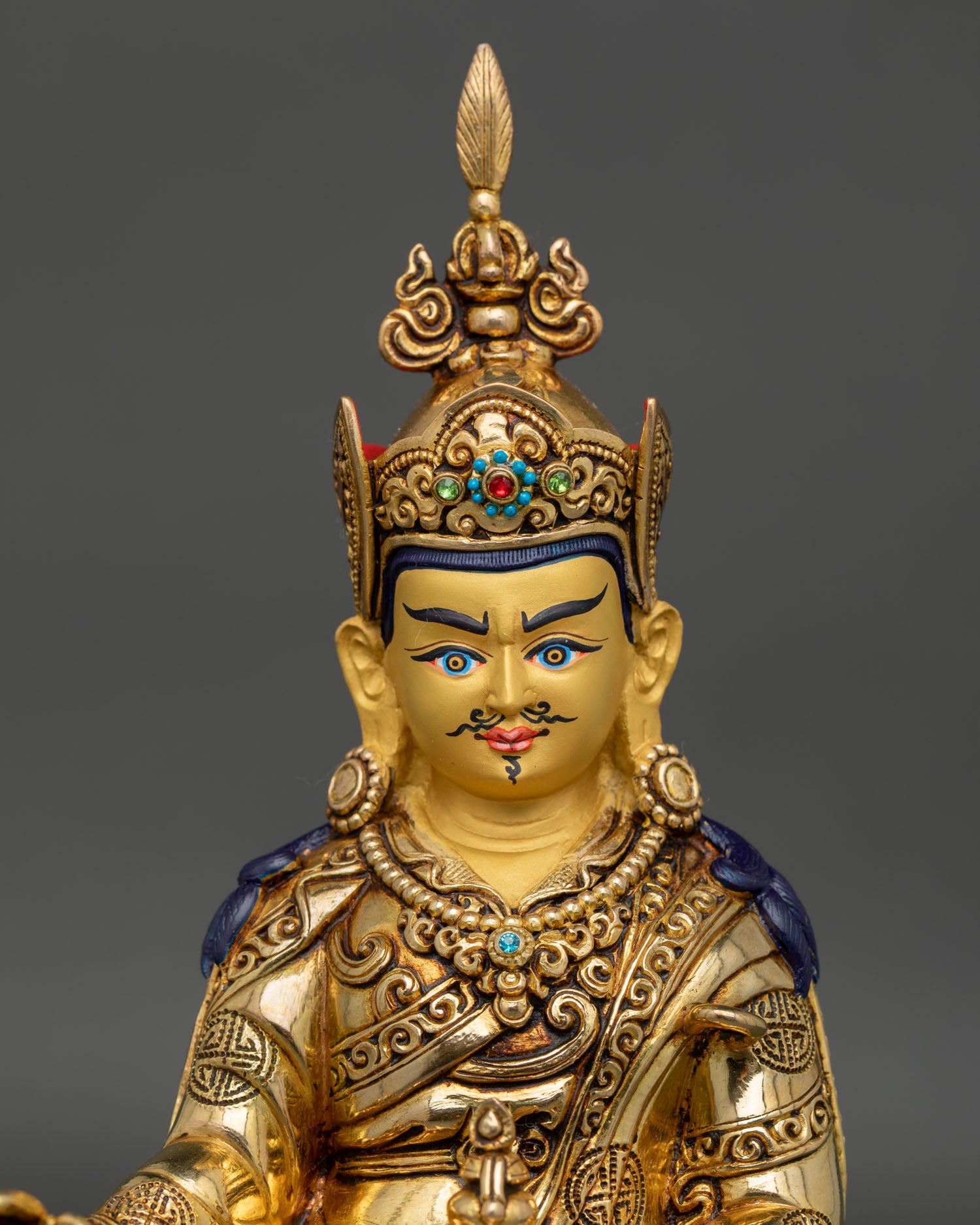 Close-up and detailed view of Guru Rinpoche statue featuring serene gold-painted face, crown, jewelry, and Himalayan craftsmanship.