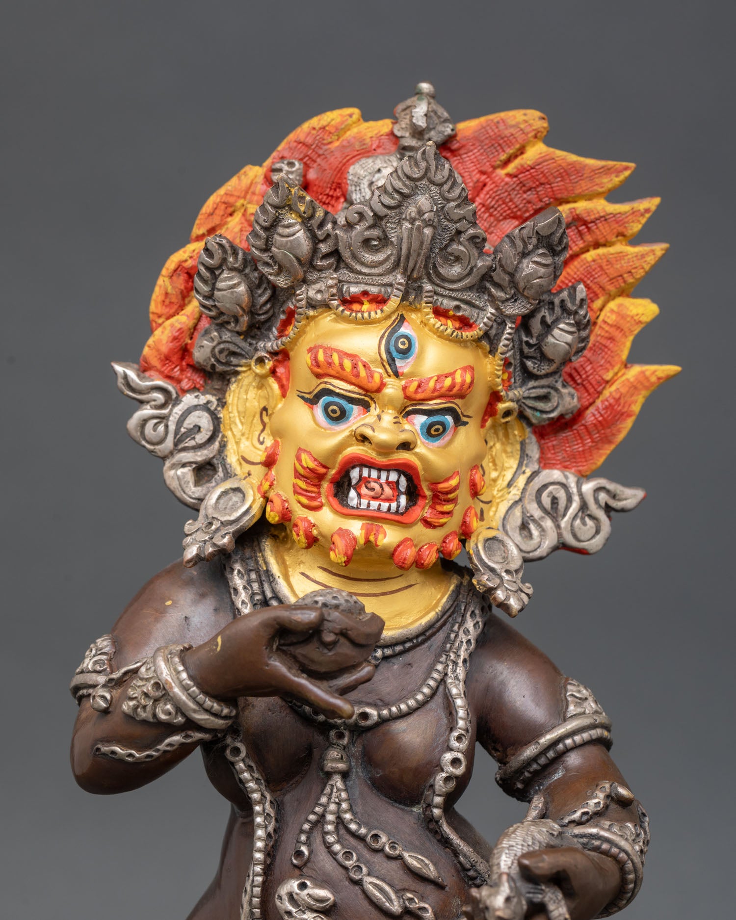 Close up of Black Dzambhala face third eye gold painted copper Tibetan Buddhist deity