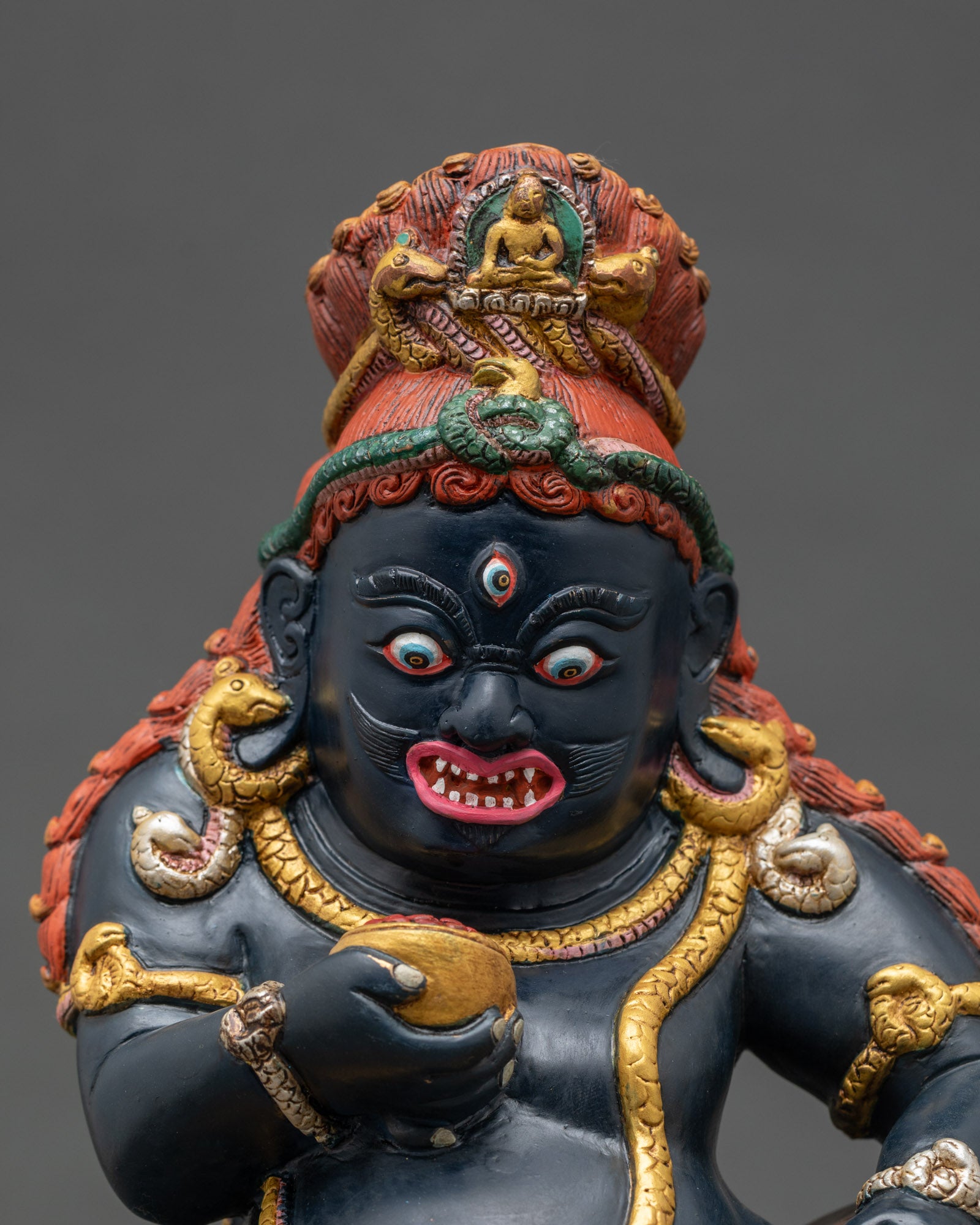 Close up Black Dzambhala face three eyes kapala mongoose Himalayan tantric sculptur