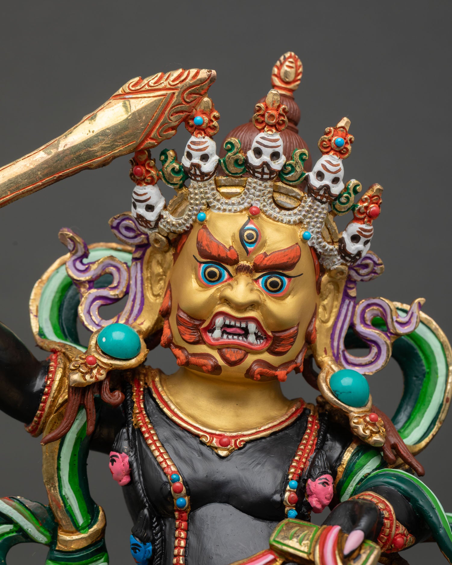 Close up Black Manjushri face with gold paint, third eye and five skull crown detail