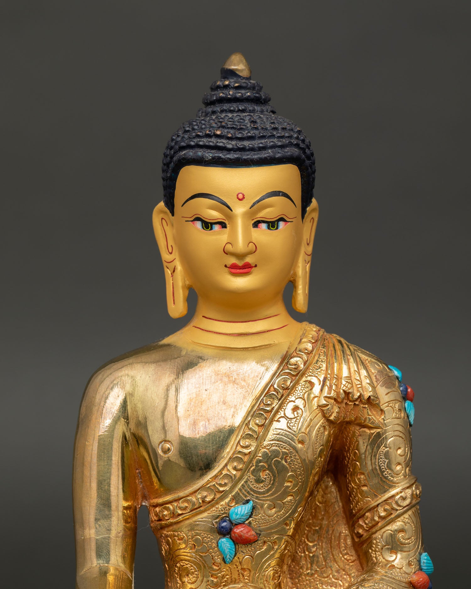 Close up Buddha Shakyamuni statue showing serene face with gold paint semi precious stone detailing