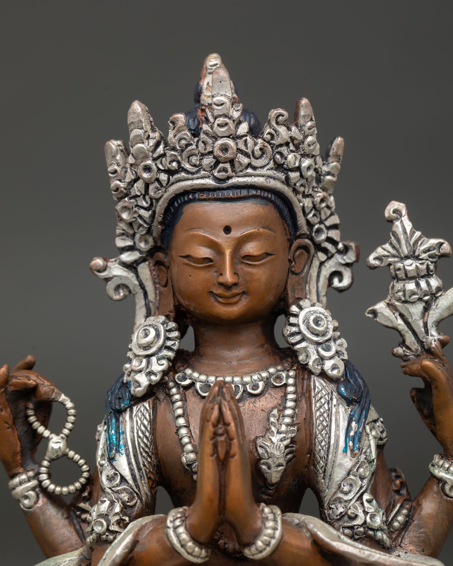 Close up Chenrezig statue, four armed Avalokiteshvara, crystal mala, lotus flower, anjali mudra, serene expression Himalayan Buddhist art