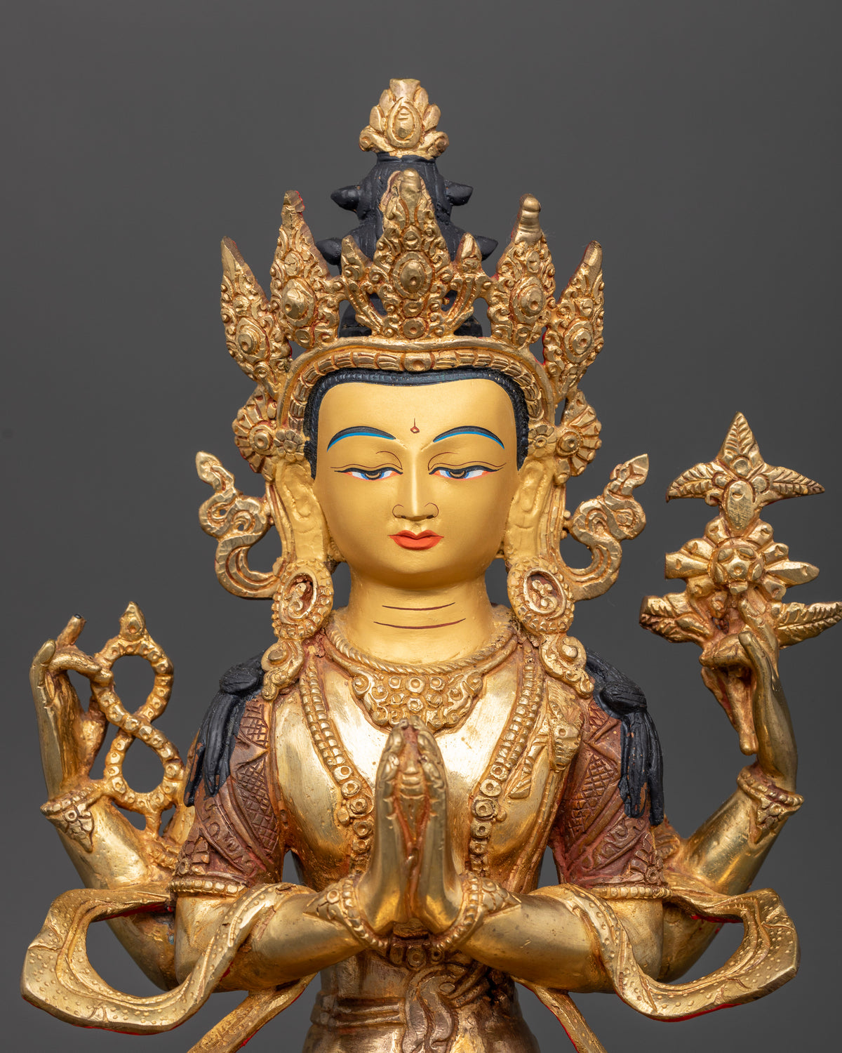 Close up of Chenrezig statue showing serene 24K gold painted face and intricate Newari details.
