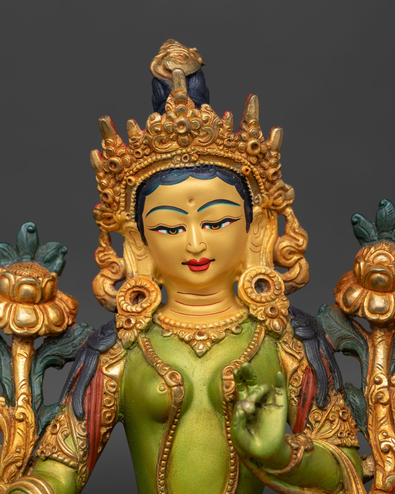 Close up detail of Green Tara face with serene gold painted expression, showcasing fine handcrafted Nepalese Buddhist sculpture artistry.