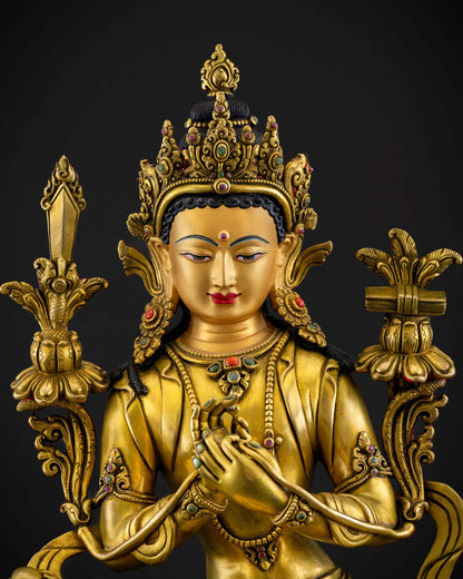 Close up detail of Manjushri face and jeweled crown showing serene expression gold fire gilded finish and intricate Newari craftsmanship