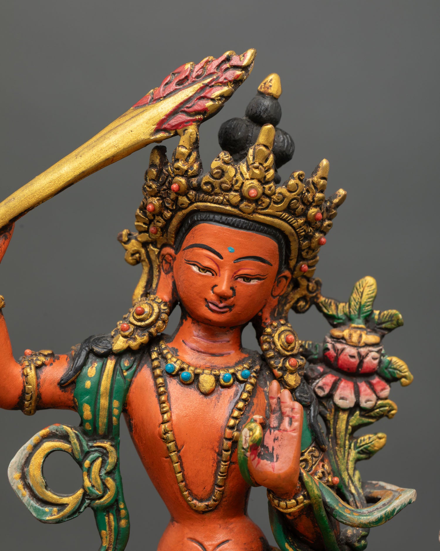 Close up detail of Manjushri face and upper body showing serene expression hand painted acrylic finish ornate jewelry and sacred Nepalese Newari craftsmanship