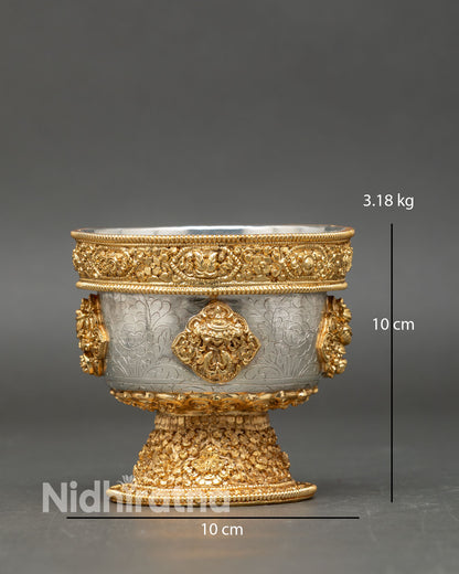 Close up detail water offering bowl showing intricate engraved sacred symbols copper craftsmanship and refined gold and silver plated Himalayan Buddhist ritual design