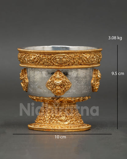 Close up detail water offering bowl showing intricate engraved symbols copper craftsmanship and refined gold and silver plated Himalayan Buddhist ritual design