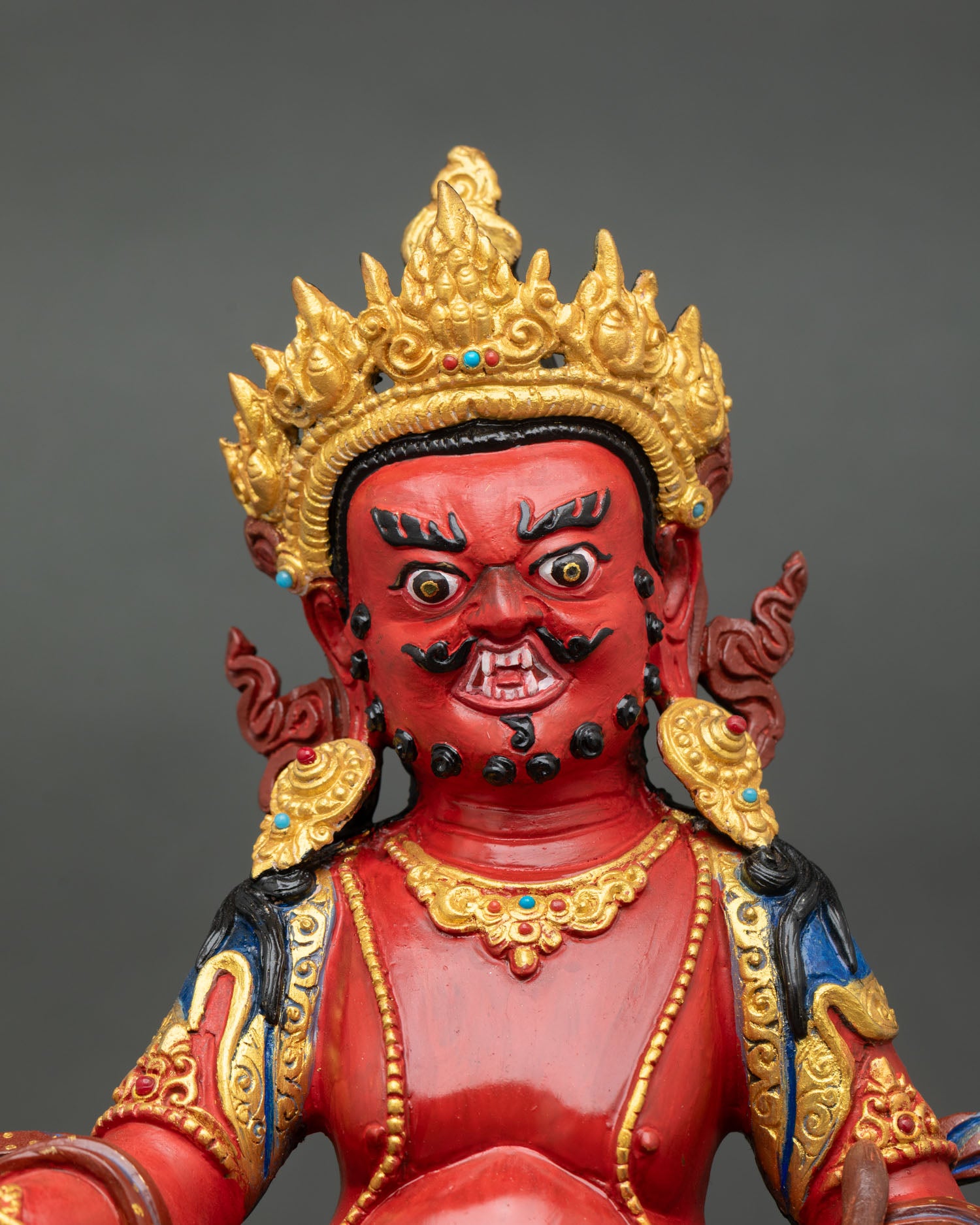 Close-up Dzambhala face detail with gold gilded finish, acrylic painting, Himalayan artisan craftsmanship, sacred Buddhist wealth deity expression