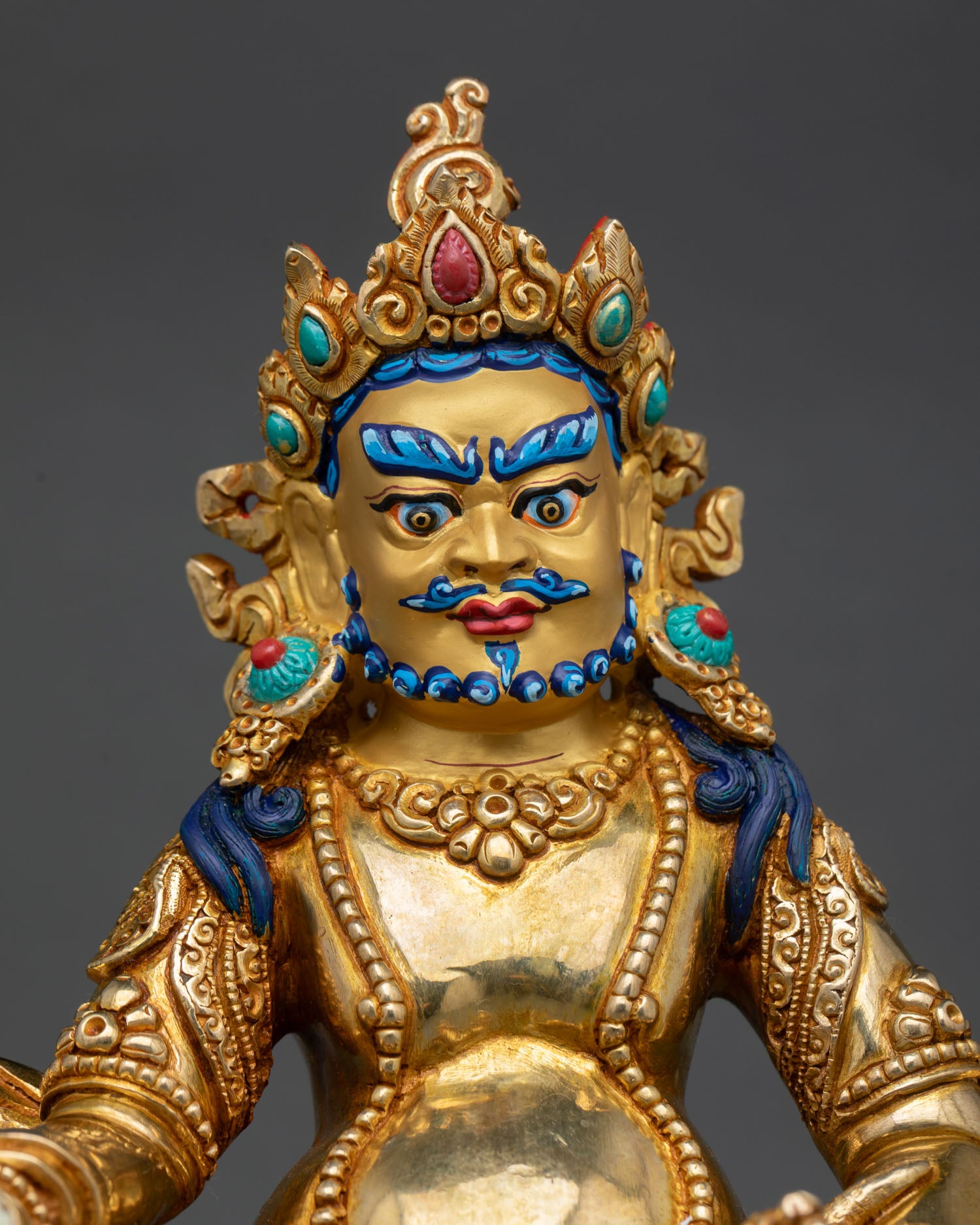 Close up Dzambhala gold painted face detail, copper statue with 24K gold gilding, semi precious stone inlay, Nepalese craftsmanship