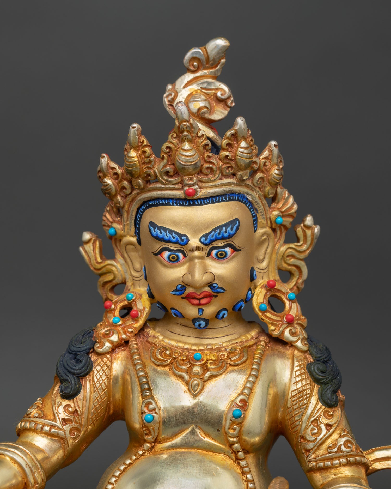 Close-up Dzambhala gold-painted face, wealth deity art
