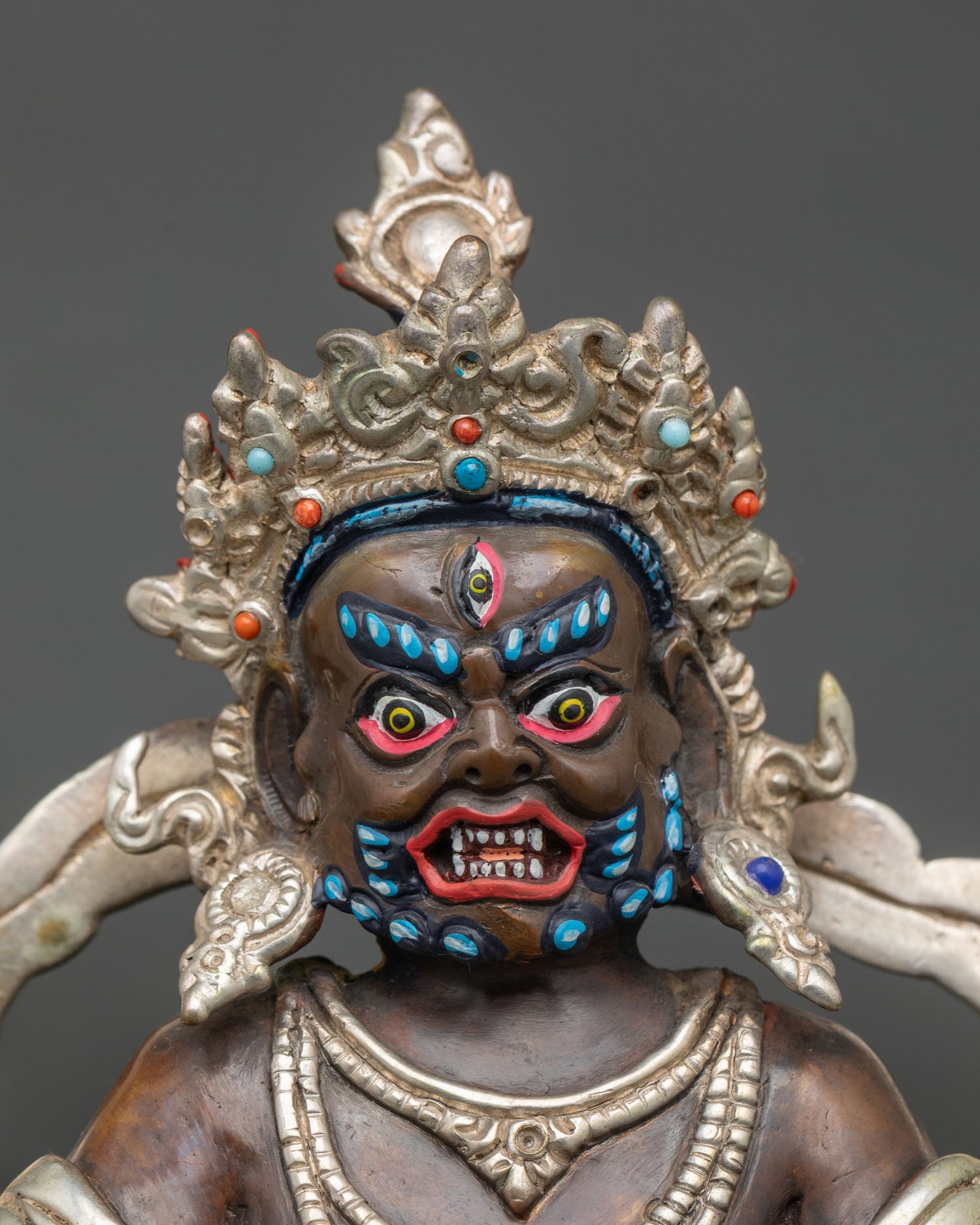 Close up of the Dzambhala statue showing semi-precious stones, crown, and ornaments detail.