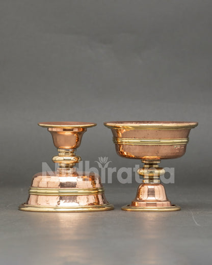Close up of engraved two butter lamps, copper Tibetan Buddhist ritual set