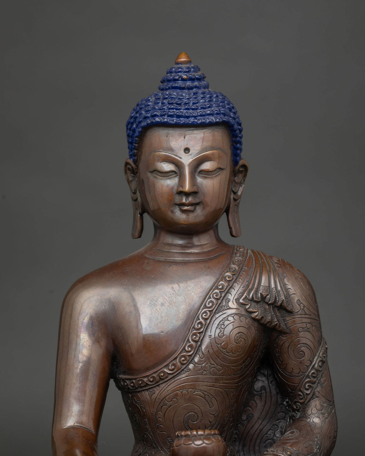 Close up of the Buddha's face showing the chemically oxidized copper patina.